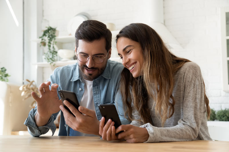 couple smiling and reviewing footage on phone